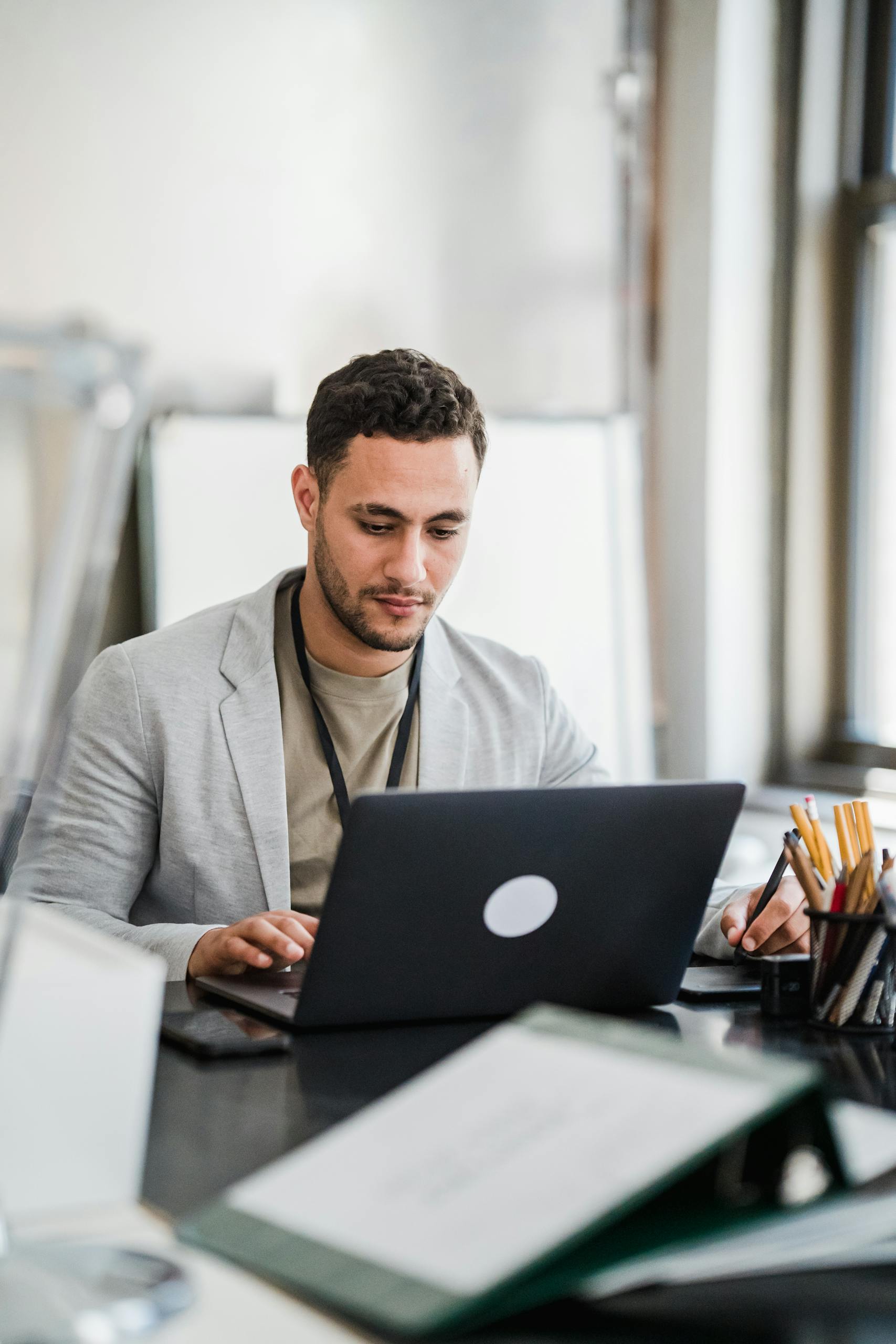 Focused man working on a laptop in a modern office setting, emphasizing productivity and technology.